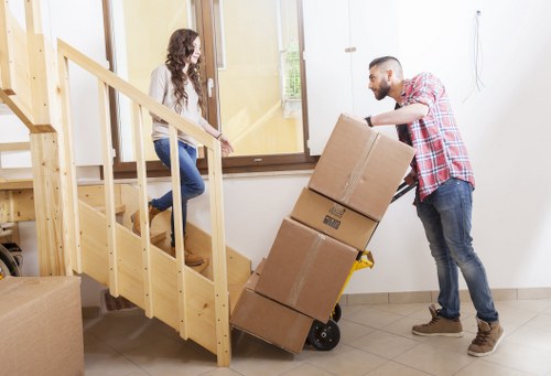 Moving a piano through a narrow hallway in Sutton with protective padding
